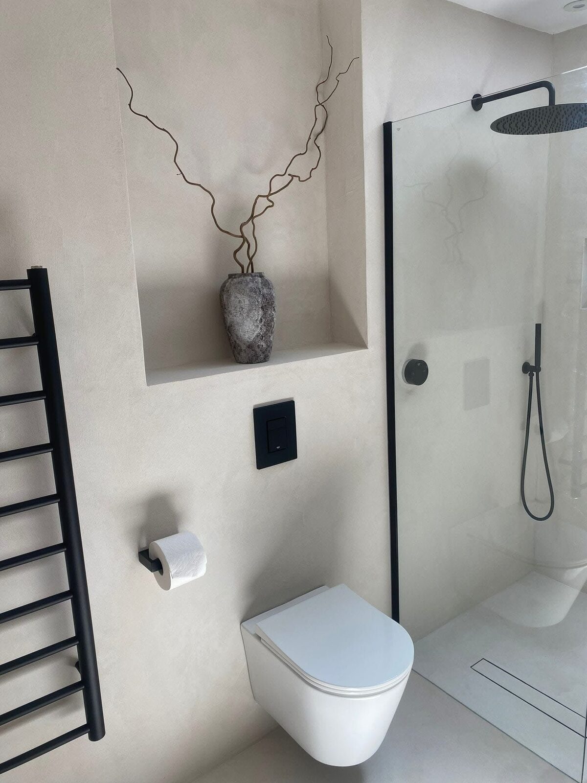 Cream microcement shower with recessed niche and black towel rail
